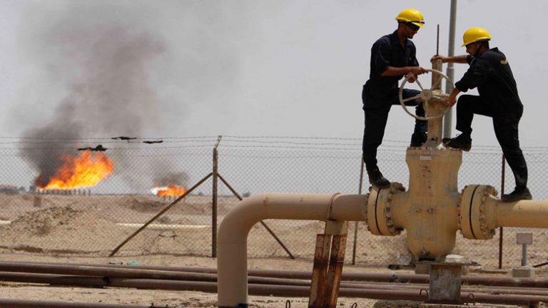 صورة فيها رجلان أثناء عملية التنقيب عن النفط والغاز وخلفهما شعلة نار